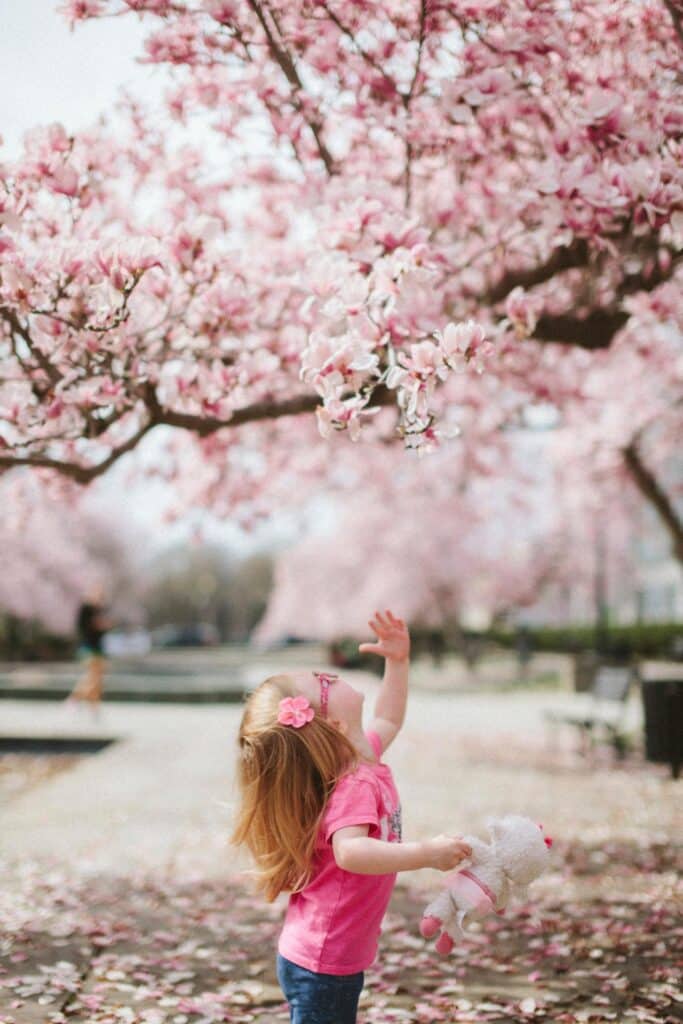 girl-child-looking-at-flowers-on-tree